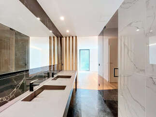 Experience modern luxury in this stunning bathroom featuring a sleek double vanity with contemporary faucets and a large, illuminated mirror.