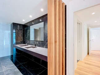 Experience modern luxury in this stunning bathroom featuring a sleek double vanity with integrated sinks and a dramatic black marble accent wall.