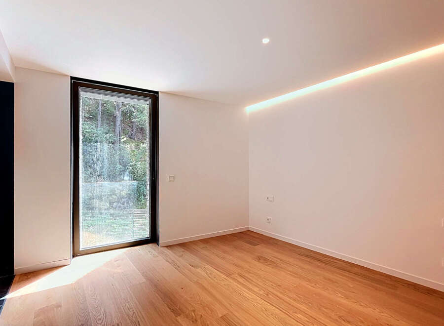 Experience modern living in this bright and airy room featuring a large window with lush green views.