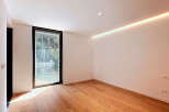 Experience modern living in this bright and airy room featuring a large window with lush green views.