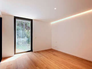 Experience modern living in this bright and airy room featuring a large window with lush green views.