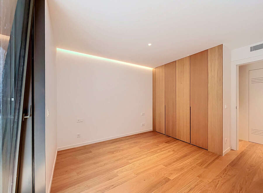 Experience modern living in this beautifully designed room featuring a sleek, built-in wooden wardrobe that offers ample storage.