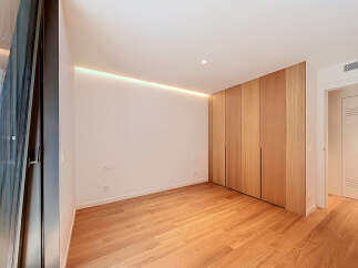 Experience modern living in this beautifully designed room featuring a sleek, built-in wooden wardrobe that offers ample storage.