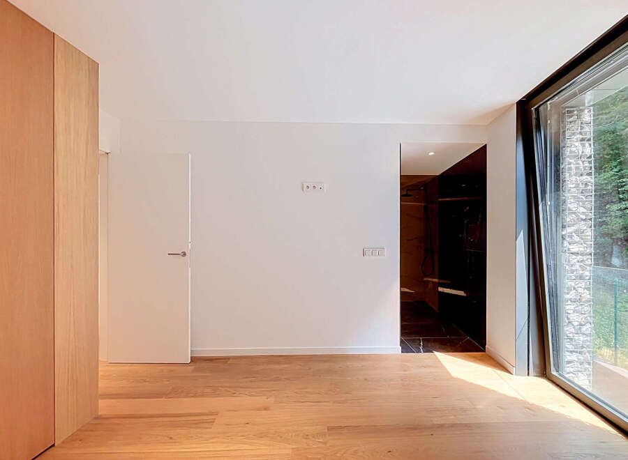 Experience modern living in this spacious room featuring a sleek wooden wardrobe and a minimalist interior.