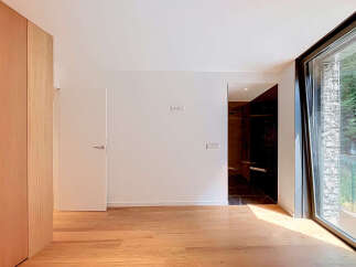 Experience modern living in this spacious room featuring a sleek wooden wardrobe and a minimalist interior.