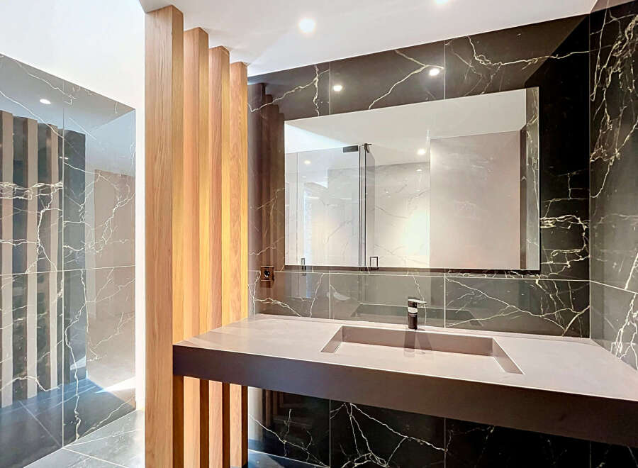 Experience modern luxury in this stunning bathroom featuring a sleek vanity with an integrated sink, complemented by dramatic black marble walls.