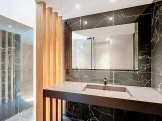 Experience modern luxury in this stunning bathroom featuring a sleek vanity with an integrated sink, complemented by dramatic black marble walls.