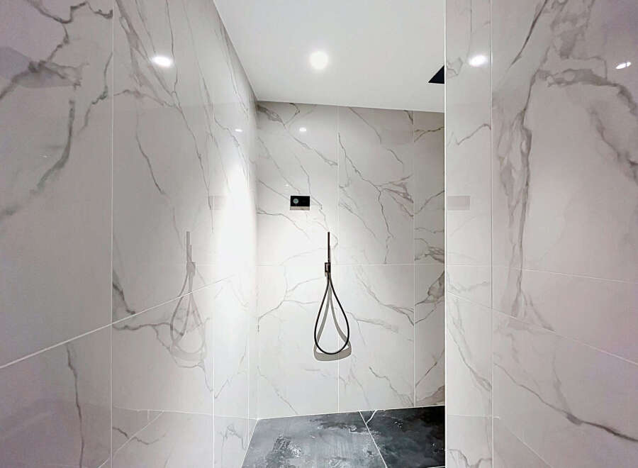 Step into this modern shower featuring elegant marble-patterned tiles that create a luxurious and spa-like atmosphere.