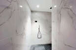 Step into this modern shower featuring elegant marble-patterned tiles that create a luxurious and spa-like atmosphere.