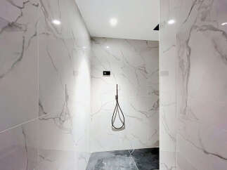 Step into this modern shower featuring elegant marble-patterned tiles that create a luxurious and spa-like atmosphere.