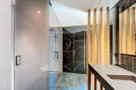 Experience modern luxury in this stunning bathroom featuring a sleek glass-enclosed shower with a rainfall showerhead and a minimalist toilet.