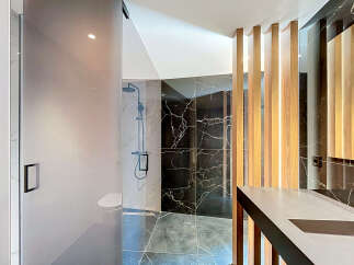 Experience modern luxury in this stunning bathroom featuring a sleek glass-enclosed shower with a rainfall showerhead and a minimalist toilet.
