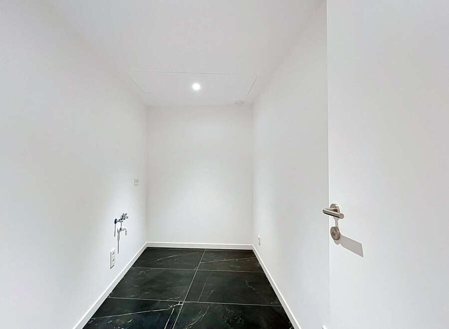 Discover this modern, minimalist room featuring sleek black marble tile flooring and crisp white walls.