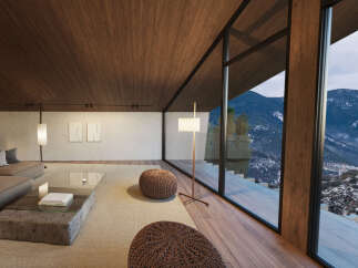 Mountain view living room with floor to ceiling windows, hardwood floors, and cozy seating.
