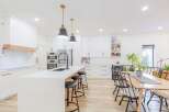 This stunning kitchen boasts a modern design with sleek white cabinetry and a spacious island.