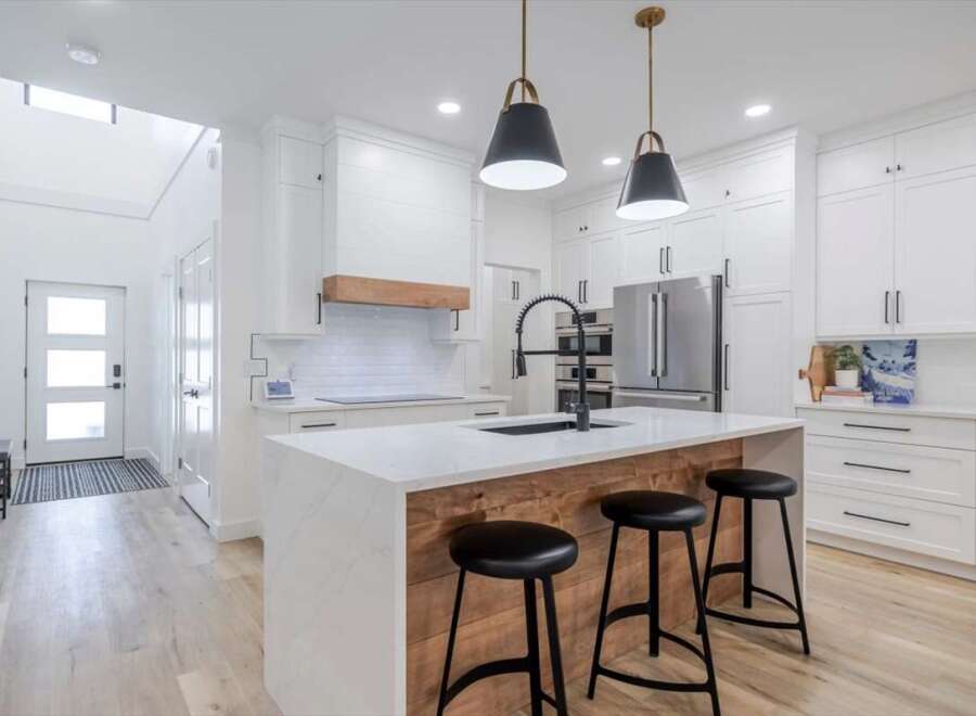 This stunning kitchen boasts a modern design with sleek white cabinetry and a spacious island.