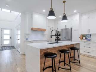 This stunning kitchen boasts a modern design with sleek white cabinetry and a spacious island.