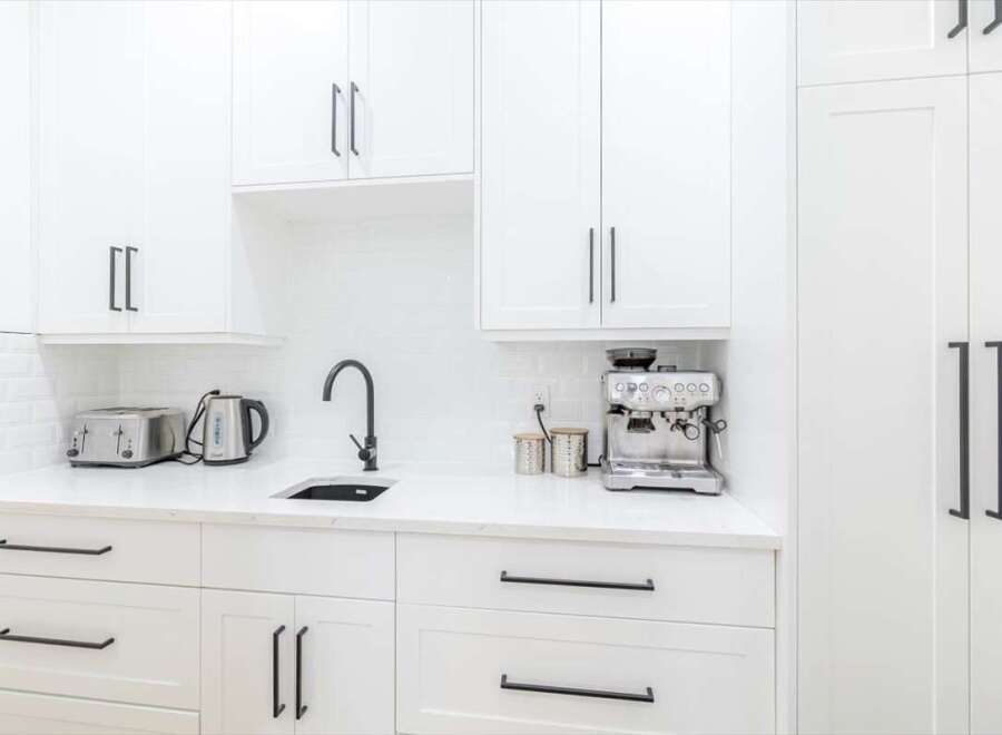 This stunning kitchen boasts a sleek, modern design with pristine white cabinetry and countertops.