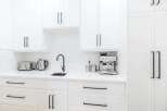 This stunning kitchen boasts a sleek, modern design with pristine white cabinetry and countertops.