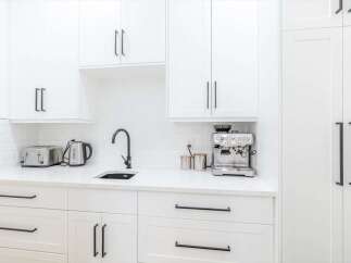 This stunning kitchen boasts a sleek, modern design with pristine white cabinetry and countertops.