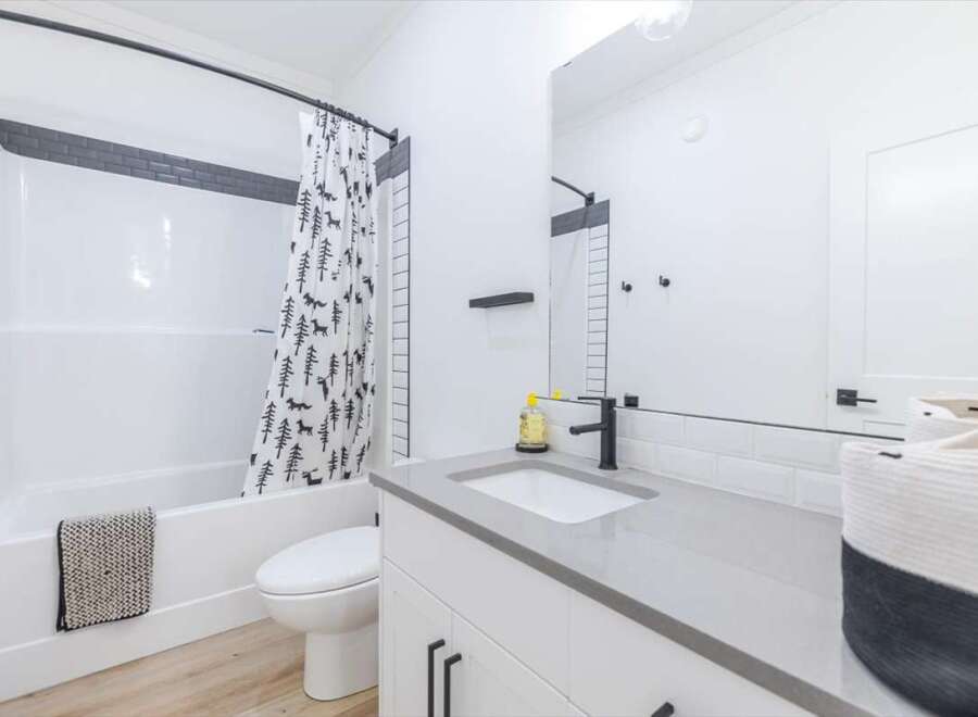 Step into a modern bathroom oasis! This space features a sleek vanity with a gray countertop and black fixtures.