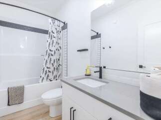 Step into a modern bathroom oasis! This space features a sleek vanity with a gray countertop and black fixtures.
