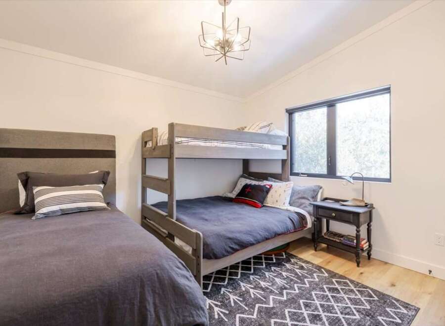 This cozy bedroom features a stylish bunk bed and a comfortable single bed, perfect for accommodating guests or family members.
