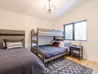 This cozy bedroom features a stylish bunk bed and a comfortable single bed, perfect for accommodating guests or family members.