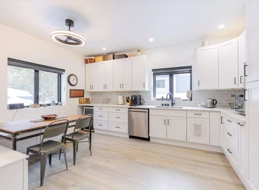 This stunning kitchen boasts modern white cabinetry, sleek stainless steel appliances, and a spacious layout perfect for culinary enthusiasts.