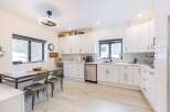 This stunning kitchen boasts modern white cabinetry, sleek stainless steel appliances, and a spacious layout perfect for culinary enthusiasts.