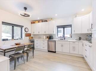 This stunning kitchen boasts modern white cabinetry, sleek stainless steel appliances, and a spacious layout perfect for culinary enthusiasts.