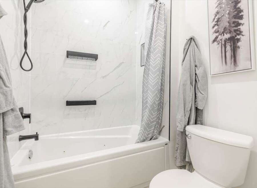 This modern bathroom features a sleek white bathtub and shower combination, perfect for relaxation.