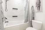 This modern bathroom features a sleek white bathtub and shower combination, perfect for relaxation.