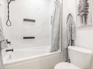 This modern bathroom features a sleek white bathtub and shower combination, perfect for relaxation.