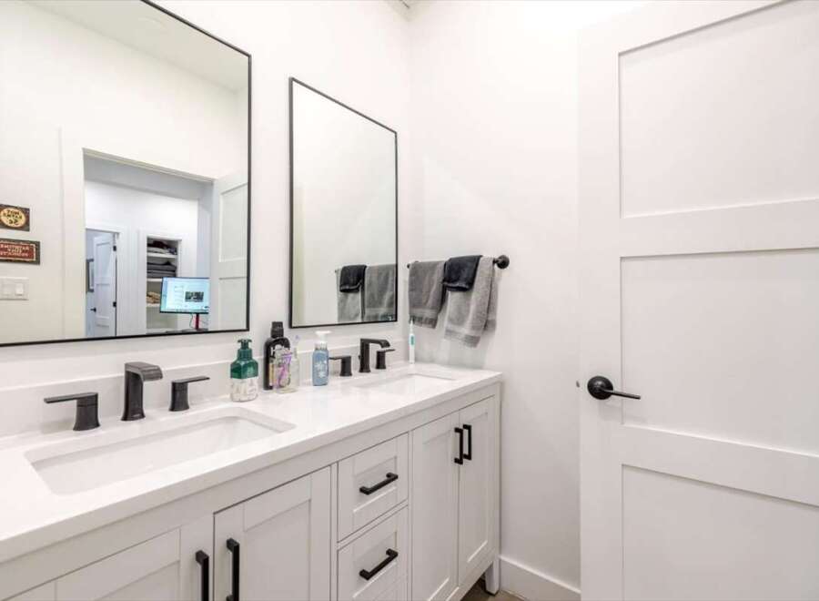 This modern bathroom features a sleek double vanity with black fixtures and a bright white countertop.
