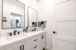 This modern bathroom features a sleek double vanity with black fixtures and a bright white countertop.