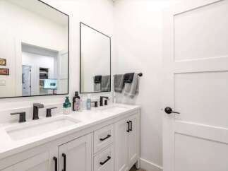 This modern bathroom features a sleek double vanity with black fixtures and a bright white countertop.
