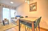 Cozy apartment featuring a comfortable sofa, a dining table with four chairs, and large windows offering plenty of natural light.