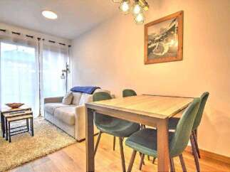 Cozy apartment featuring a comfortable sofa, a dining table with four chairs, and large windows offering plenty of natural light.