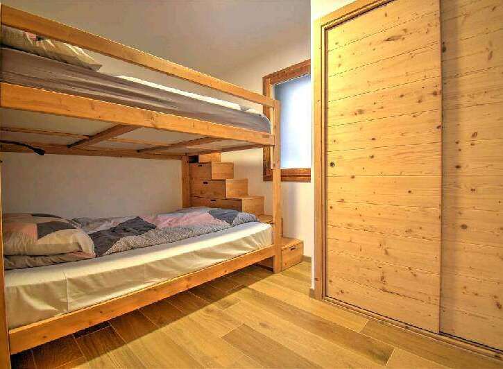 Cozy chalet bedroom with a wooden bunk bed and built-in storage.