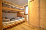 Cozy chalet bedroom with a wooden bunk bed and built-in storage.