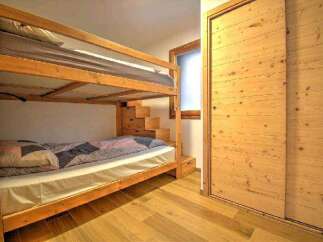 Cozy chalet bedroom with a wooden bunk bed and built-in storage.