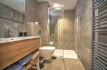 Modern bathroom with sleek wood vanity, spacious shower, and heated towel rack.