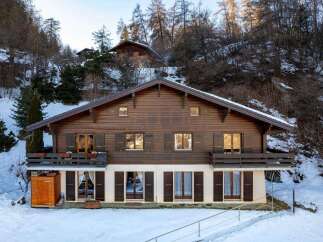 Discover the charm of this stunning wooden chalet nestled in a snowy landscape.