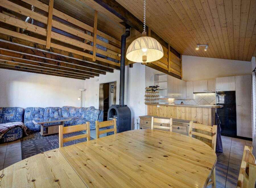This charming property boasts a cozy living space with a unique wooden ceiling design.