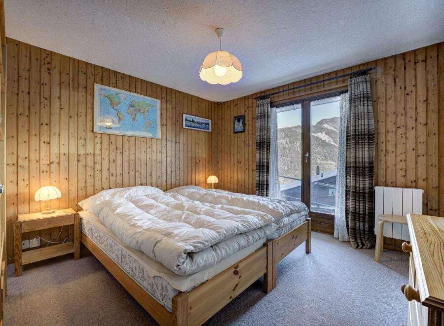 Cozy bedroom with wooden paneling and a stunning mountain view.
