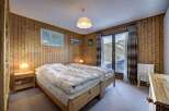 Cozy bedroom with wooden paneling and a stunning mountain view.