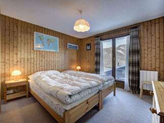 Cozy bedroom with wooden paneling and a stunning mountain view.