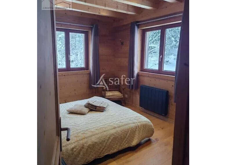 Cozy bedroom with wooden walls and ceiling, creating a warm and inviting atmosphere.