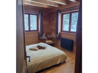 Cozy bedroom with wooden walls and ceiling, creating a warm and inviting atmosphere.